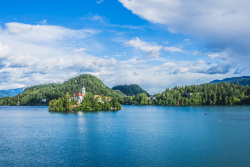 Fototapeta premium Beautiful view of blue Lake Bled, Slovenia, on a sunny day, blue sky and white clouds, church on the island.
