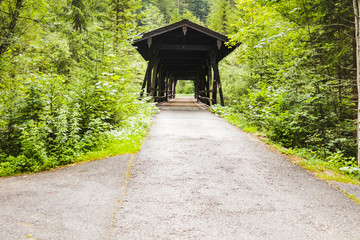 wooden covered bridge crossing a river surrounded by forest