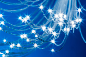 Fototapeta na wymiar Bundle of optical fibers with lights in the ends. Blue background.