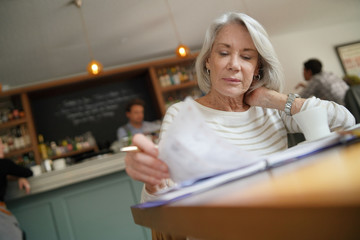 Fototapeta na wymiar Senior woman going through diary in a restaurant