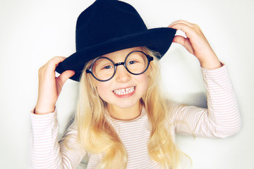 Adorable little girl wearing a hat and glasses smiling