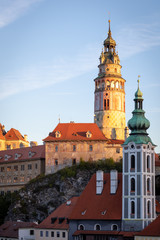 Fototapeta na wymiar View of the State Castle and Chateau Cesky Krumlov, tower of St. Jost church and historic red roof houses in Cesky Krumlov, Czech Republic, during morning sunrise