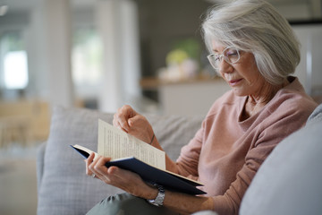  Senior woman reading on couch at home