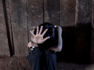 Helpless little girl sitting on floor against old earth brick wall,stop violence and abused children,human trafficking concept