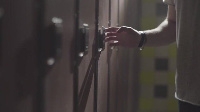 Man's hand opening locker with electric key on his wrist at gym in the changing room. Frame. Close up hand opening the locker door in the changing room of a gym.