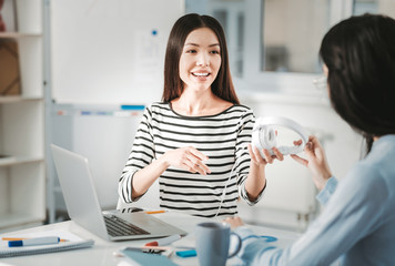 Helpful assistant giving earphones to her colleague during break