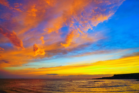 Golden clouds at sunset over the sea .