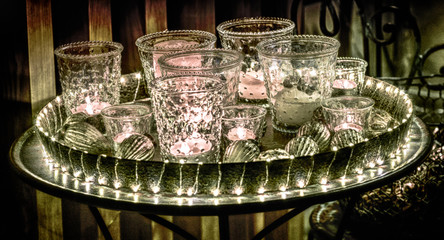 detail view of a decorative and festive Christmas holiday arrangement with glasses and candles and assorted decorative articles at night