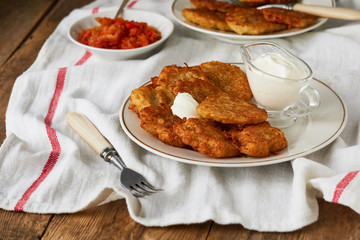 Potato fritters with sour cream and tomato sauce on a wooden table