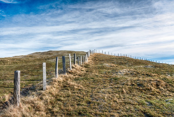 open country landcape with grassy meadow and rime and ice and old wooden fence in the middle under an expansive sky