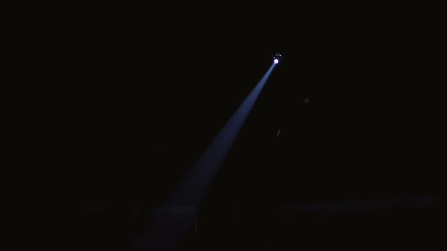 Blue light from a single spotlight through the darkness in a theater or circus during a performance. Lightning equipment.