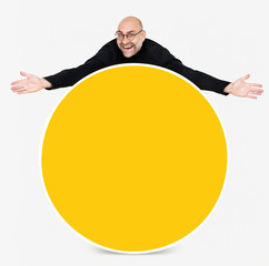 Happy man showing a round yellow board