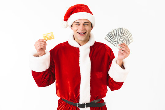 Image of happy man 30s in santa claus costume holding dollar bills and credit card, isolated on white background in studio