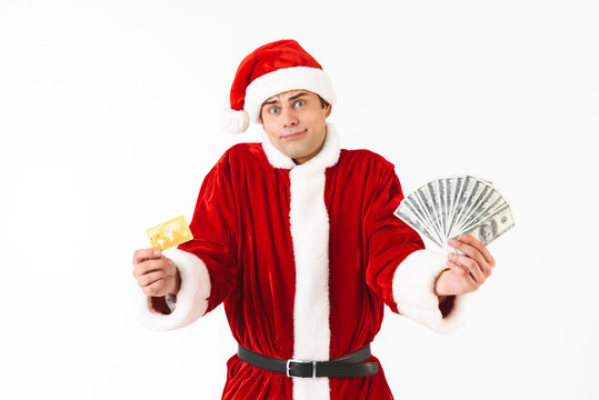 Image of caucasian man 30s in santa claus costume holding dollar bills and credit card, isolated on white background in studio