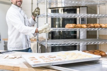 smiling male baker in white chefs uniform working at kitchen