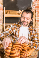 Fototapeta na wymiar Handsome seller putting pastry in wicker basket