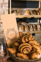 close up of fresh baked croissants in wicker basket with menu