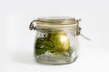Gold Christmas ball and spruce branch in a glass jar. Isolated on white.