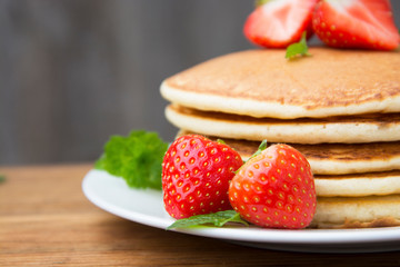 Homemade american pancake with fresh  strawberries, on rustic wooden board. Healthy breakfast. 