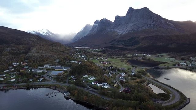 Aerial pan over a town in Norway with scenic snow capped mountains in the background 
