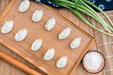 Dumplings, flour, leeks, rolling sticks, on the wooden table