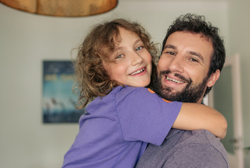 Content dad holding his son in his arms at home