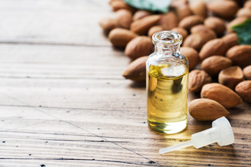 Almond oil in bottle on wooden background. Concept Spa, aromatherapy and medicine. Copy space