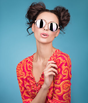 Colorful Studio portrait of a beautiful young woman in sunglasses. A stylish haircut, bright red blouse