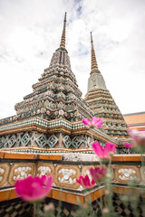 Fototapeta premium Vertical photo with flowers of Wat Pho or Temple of the Reclining Buddha in Bangkok, Thailand. One of the most attractive landmark in Thailand.