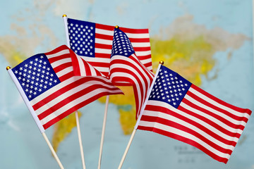 The four small flags of the United States waving in the wind against the background of the world map. Сoncept of  USA Independence Day . Celebrated on July 4.
