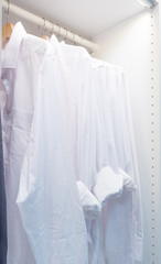 Modern interior wardrobe with shirt and dress in shelf.
