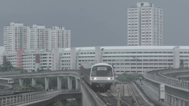 Modern subway train on a railroad in Sinapore on a city buildings background. Shot. Singapore mass rapid train MRT travels on the track.