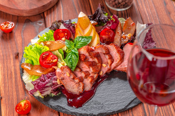 Tasty sliced roast duck breast with fresh vegetable salad closeup on a plate.