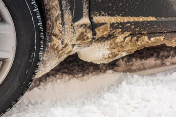 Adhered to the body of the car dirty snow from the road. photo close-up of car details. rusty car, metal corrosion and traces of reagents, winter Moscow city.