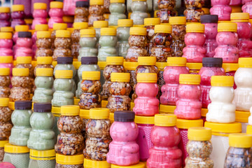 Many transparent plastic jars with yellow lids in the shape of a bear with green, pink honey mixed with nuts. Concept of local Siberian delicacies and specialties