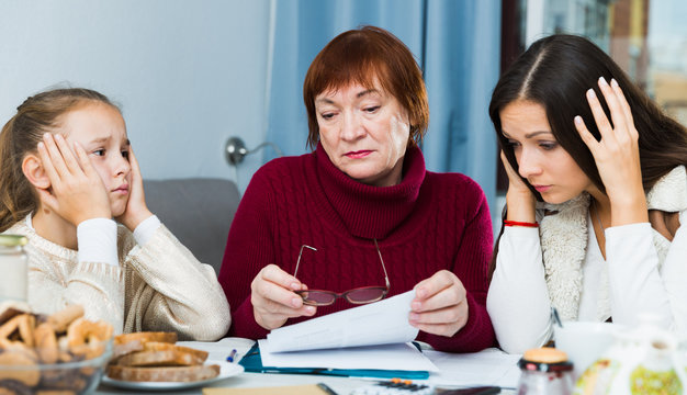 Senior lady with adult family looking worriedly at papers