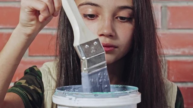 Teenager watching paint fall off from paintbrush