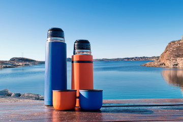 two colored thermos on the background of the sea bay