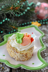 Delicious New Year's biscuit cake with butter cream, decorated with flowers from the cream is on a porcelain plate a plate shaped like Christmas tree next to Christmas balls and beads