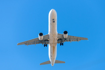 A white airplane flying in a clear pale blue sky