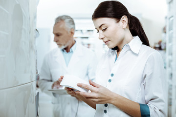 Fototapeta premium Attentive young assistant checking expire date of pills