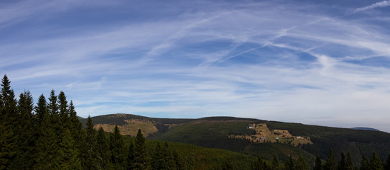 Panoramatic view of the green summer mountains and part of the forest with bloudy blue sky in the background, Modry dul and Studnicni hora in Krkonose (Giant Mountains), Czech Republic