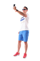 Happy smiling man tourist in summer clothes taking high angle selfie photos. Full body isolated on white background. 