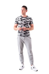 Fototapeta premium Young adult man in sporty clothes and army t-shirt looking up and thinking. Full body isolated on white background. 