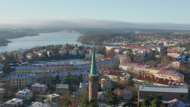 Aerial footage of the Stora Essingen church tower with a golden christian cross on top in Stockholm, Sweden