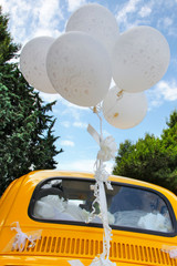 dettaglio di palloncino legati ad una macchina gialla su sfondo azzurro © alex.pin