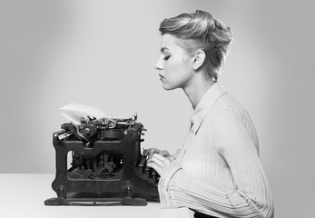 Young blonde female writer using typing machine, black and white