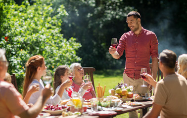 leisure, holidays and people concept - happy family having festive dinner or summer garden party...