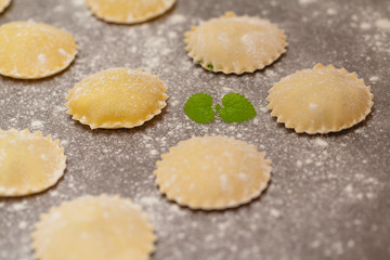 Fototapeta na wymiar Tasty raw ravioli with flour on dark background. Process of making italian ravioli.