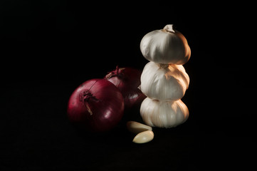 Composition of two red onions and three heads of garlic on a black background
